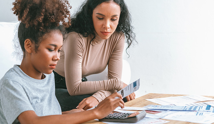 Mother and daughter reviewing financial documents and using a calculator for college expenses.