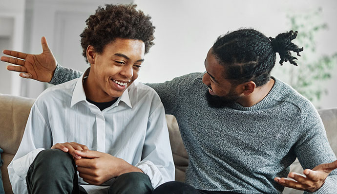 Father and son having a heartfelt conversation while sitting on a couch.